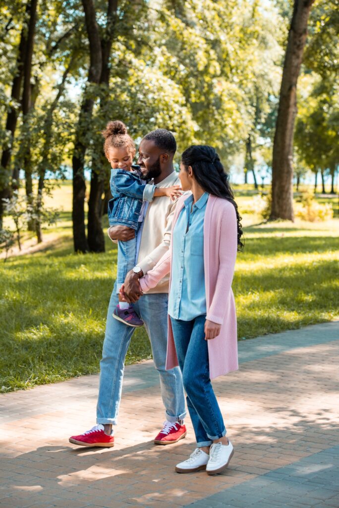 african american parents and daughter walking together in park